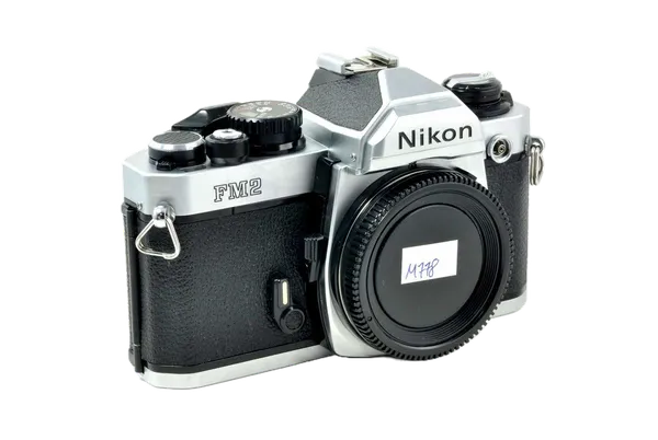 A vintage Nikon film camera with a large lens, silver and black body, and various dials and buttons.